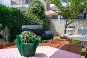 Close-up of Texas BBQ smoker grill with garden and catering table