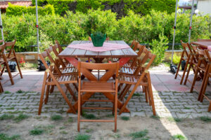 Outdoor BBQ catering table setup with wooden chairs and red checkered tablecloth