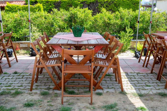 Outdoor BBQ catering table setup with wooden chairs and red checkered tablecloth
