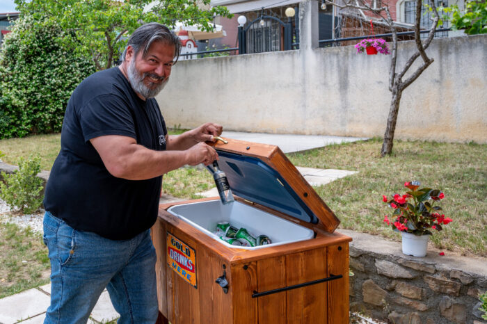 Guest happily opening vintage wooden cold drinks cooler at BBQ event