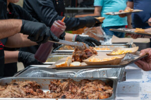 BBQ chef serving smoked meat with sauce and sides at Texas catering event