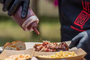 Adding BBQ sauce on smoked pulled pork at Texas BBQ catering buffet