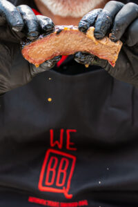 BBQ chef showing juicy slice of smoked brisket at Texas smoked BBQ catering